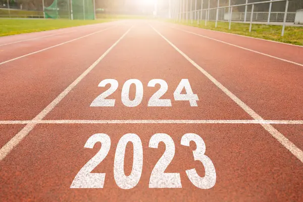Mutlu yıllar 2024, yeni yılın başlangıcını simgeliyor. 2024 yılına kazınmış atletizm pistinde koşmaya hazırlanan bir adamın arka görünüşü. Başarının amacı. Yeni yıla hazırlanıyorum..