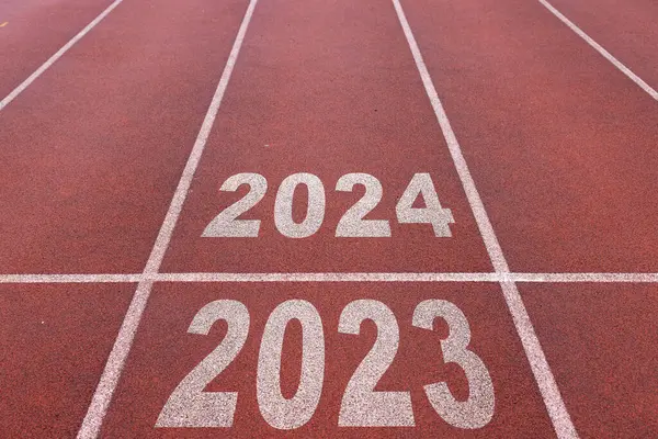 Mutlu yıllar 2024, yeni yılın başlangıcını simgeliyor. 2024 yılına kazınmış atletizm pistinde koşmaya hazırlanan bir adamın arka görünüşü. Başarının amacı. Yeni yıla hazırlanıyorum..
