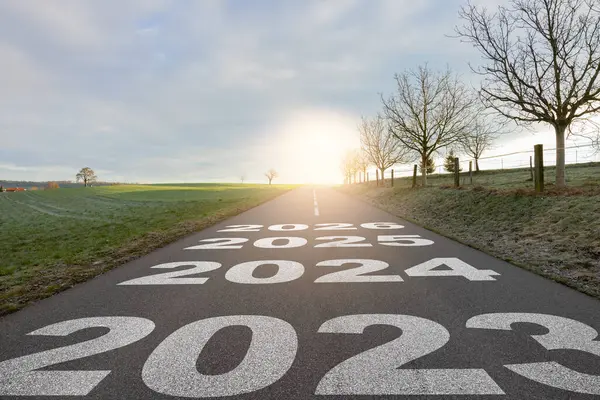 Yeni yıl 2024 ya da yeni yıl konsepti. Metin Yılı 2023, 2024, 2025, 2026 gün batımında asfalt yolun ortasında yazılmış. Planlama, hedef, meydan okuma, yeni yıl çözümü kavramı.