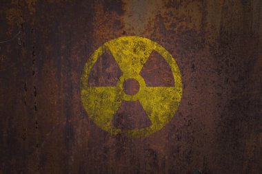 Radyoaktif (iyonlaştırıcı radyasyon) yuvarlak sarı ve siyah tehlike sembolü büyük paslı bir metal duvara koyu renkte grunge dokuya boyanmış. Nükleer, radyoaktif alarm konsepti.