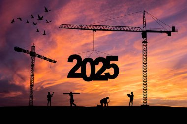 İnşaat vinçlerinin inşa edildiği inşaat alanının silueti 2025 yılının yeni yılını gün batımında karşılamaya hazır olun..