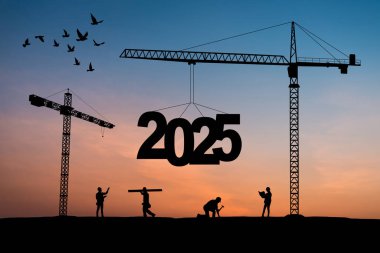 İnşaat vinçlerinin inşa edildiği inşaat alanının silueti 2025 yılının yeni yılını gün batımında karşılamaya hazır olun..