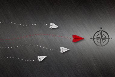 Liderlik kavramı, siyah metal arka planda beyaz uçağı pusulaya götüren kırmızı lider uçağı..