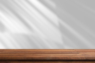 Beyaz duvarlı, ahşap bir masa ve pencereden süzülen güneş ışığı..