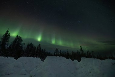 Gece gökyüzünde Aurora Borealis. Kutup ışıkları ve yıldızlı gökyüzü. Dünya atmosferinde yeşil ışık dalgaları