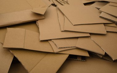 Büyük bir yığının içinde bir sürü kesik karton var. Fotoğraf, karton ambalaj tarafından üretilen atığın miktarını gösterir.