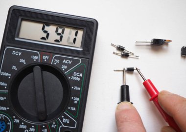Yarı iletken elektronik bileşenler. Bir beyaz üzerinde dijital çoklu metre ile diyot testi.