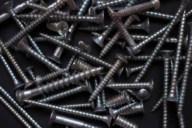 Siyah üzerine vida yığını. Karışık ahşap vida desenli endüstriyel arka plan. 