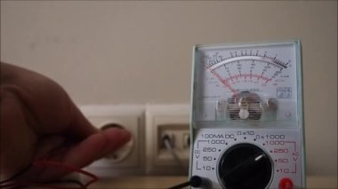 Voltaj elektrik kaynağını ölçüyorum. Elektrikçi analog voltmetre ile elektrik prizini test ediyor. 