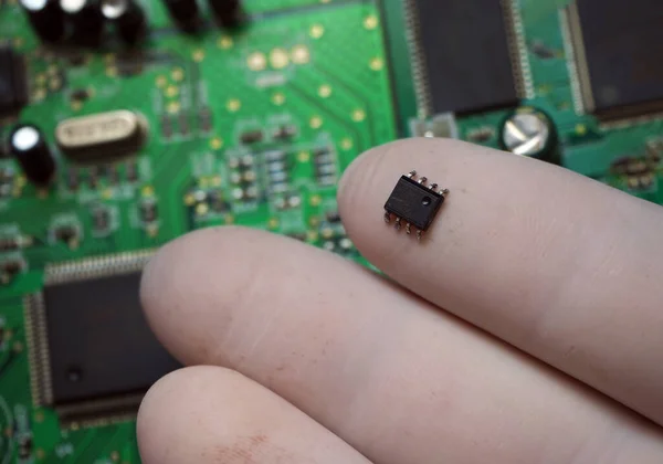 Inserting microchip onto an electronic card. Surface-mount chip removed from the board.