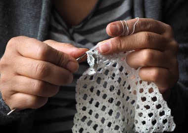 Tığ işi eller. Bir kadının elinde beyaz dantel örgü..        