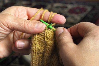 Örgü ören ellerin yakın çekimi. Kadın elleri bej bir kazak örüyor.. 