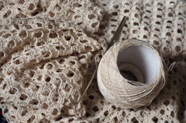 Örgü örülmüş bir kumaş ve örgü iğneli bir iplik yumağı. Tığ işi arkaplan.   