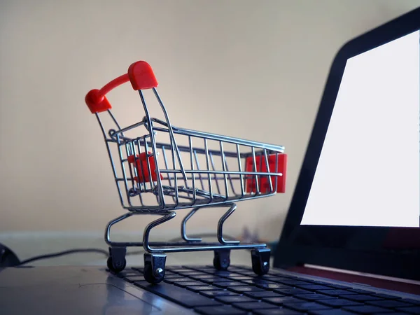 Retail trade or e-commerce. Empty shopping trolley going into the blank screen computer. Cart into the internet store.