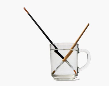 Işığın kırılması. Bir bardak suyun içinde boya fırçaları, ışık kırılması..          