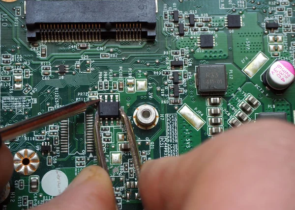 Technician replaces chip on a electronic circuit board.