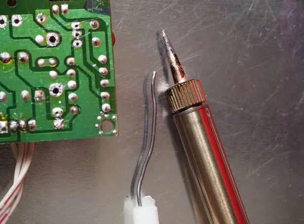 Soldering iron and solder on the electronics repair bench. Focused on soldering iron.