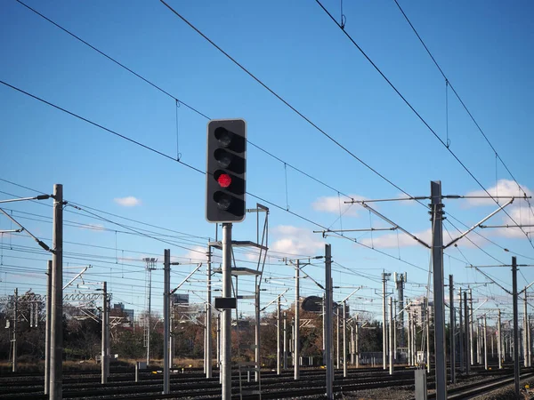 Electric high-speed train lines and traffic signaling systems. Railway signal lamp on rail and electrical wires. Red light is on.