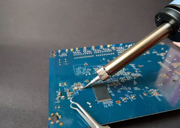 Working with soldering iron in electronic components. Surface-mount elements on the circuit board.