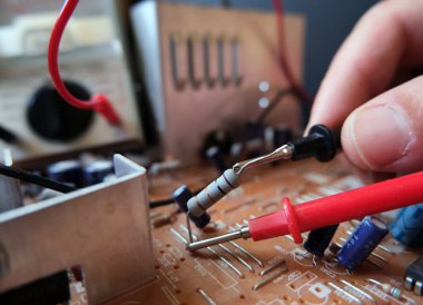 Elektrik teknisyeni elektronik bileşenleri orinted devre kartında test ediyor. Direnişe odaklanmış..