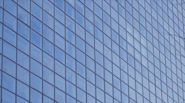 Şehirdeki mavi gökyüzünü yansıtan uzun gökdelen pencereleri