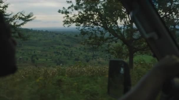 从森林和茅草屋中的非洲土路的汽车乘客一边往外看 — 图库视频影像