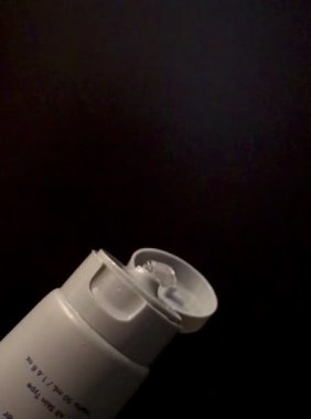 Siyah arka planda bir şişe krema.