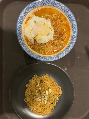 İki kase erişte, biri et suyu ve yumurta, diğeri tepsi.