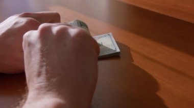 Bir adamın eli, ahşap kahverengi bir masaya 100 dolarlık banknot koyar. Bir kadının eli, üzerinde bir araba anahtarı taşır. Anahtarlığı ve parayı da götürdüler. Araba satın alma fikri..