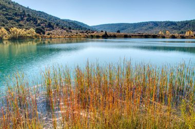 Sonbahar renklerinde dağlarla çevrili bir göl.