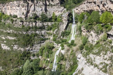 Şelale sularını Sant Miquel del Fai Doğal Alanı, Katalonya, İspanya 'daki kayalar ve bitki örtüsü arasında akıyor.