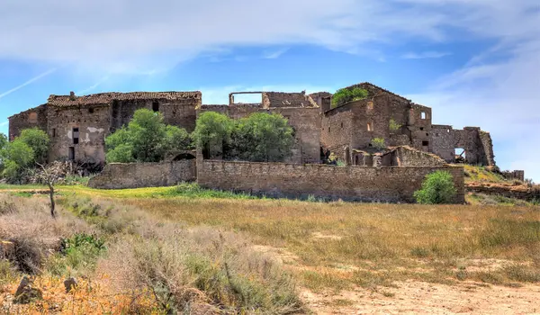 stock image Depopulated town of Conill, Lerida, Spain, with its houses in ruins. Blue sky with clouds.