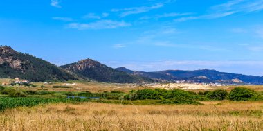 Traba lagünü ve kum tepeleri, Galiçya, İspanya 'da dağlar ve bitki örtüsüyle çevrili..
