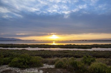 Ufuktaki son güneş ışınları Ebro Delta Doğal Parkı 'ndaki bulut kaplı koyu aydınlatıyor..