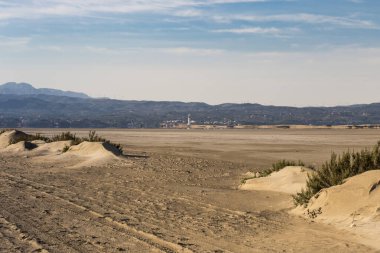 Punta del Fangar 'ın uçsuz bucaksız manzarası, Ebro Delta' daki dağlar ve ufuktaki bulutlarla kaplı deniz feneri..