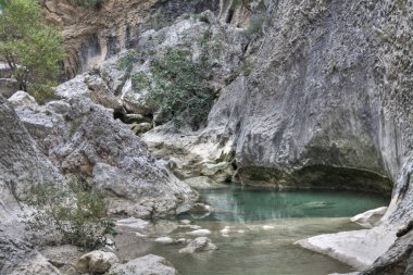 Contrast of turquoise water with the stones of the Alquezar canyon, in the Sierra de Guara, Huesca, Aragon, Spain. clipart