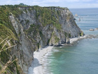 Asturias 'taki Kadavra' nın sarp kayalıkları ayaklarının dibinde ve sakin turkuaz sularla çevrili. İspanya.
