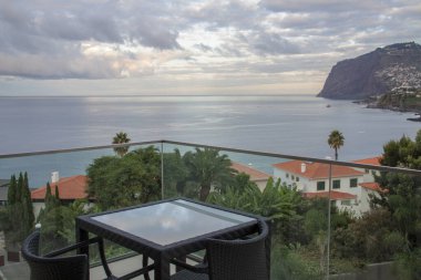 Cabo Girao balkondan gün batımında bulutlar ve denizdeki yansımalarla görüldü. Madeira Adası, Portekiz.