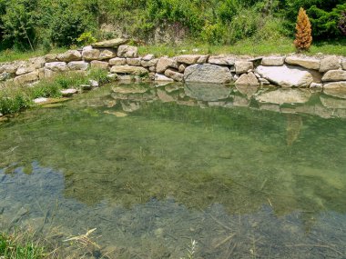 Bir göleti çevreleyen kuru taş duvar. UNESCO tarafından kültür mirası olarak kabul edilen inşaat tekniği