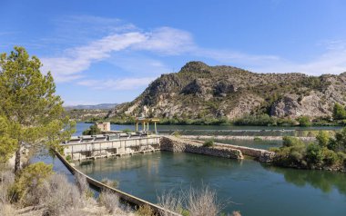 Ebro Nehri 'ndeki hidrolik altyapı ufukta bulutlu dağların yanında..