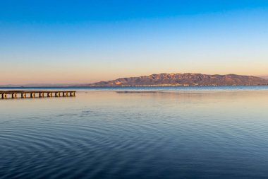 Undulating water in a sunset in the Trabucador with Sant Carles de la Rpita and the mountains in the background. clipart