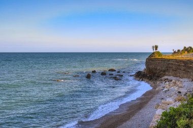 Gün batımında Costa Dorada 'da kayalar ve bitkilerle dolu bir koy manzarası. Tarragona, İspanya.