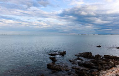 Ebro Delta, Katalonya, İspanya 'da denizin üzerinde bulutlarla sakin bir gün batımı.