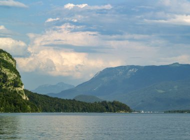 Saint Gilgen 'den Wolfgang Gölü' nün panoramik manzarası ufukta bulutlarla kaplı dağlar.