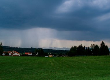 Gökyüzü kara bulutlar ve yağmurla kaplıyken Avusturya dağlarına yağan fırtınalı hava..