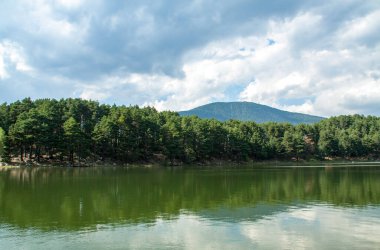 Engolaster Gölü kıyısındaki orman, Andorra 'daki suda yansıyor.