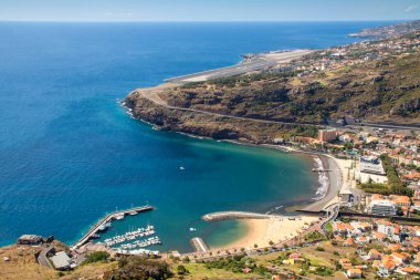 Machico şehrinin güzel bir sahili, küçük bir limanı ve arka planda havaalanı var..