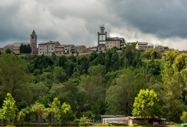 Zirvedeki Bellver de Cerdanya köyü orman ve fırtınalı bulutlarla çevrili.
