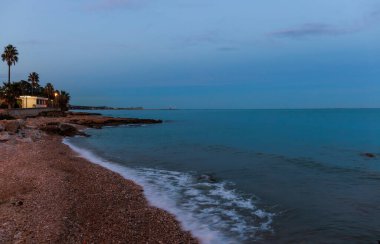 Sahilde gün batımı dalgalar Costa Dorada kıyılarına ulaşıyor.