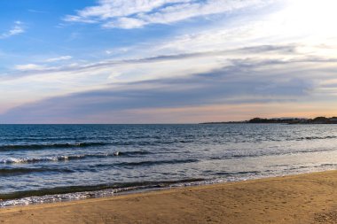 Costa Dorada sahilinde gün batımında ufuktaki bulutlar arasında pembe renkler vardı.